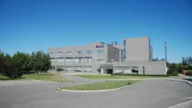 A modern multi-story building with large glass windows, located in Beijing, surrounded by greenery under a clear blue sky.