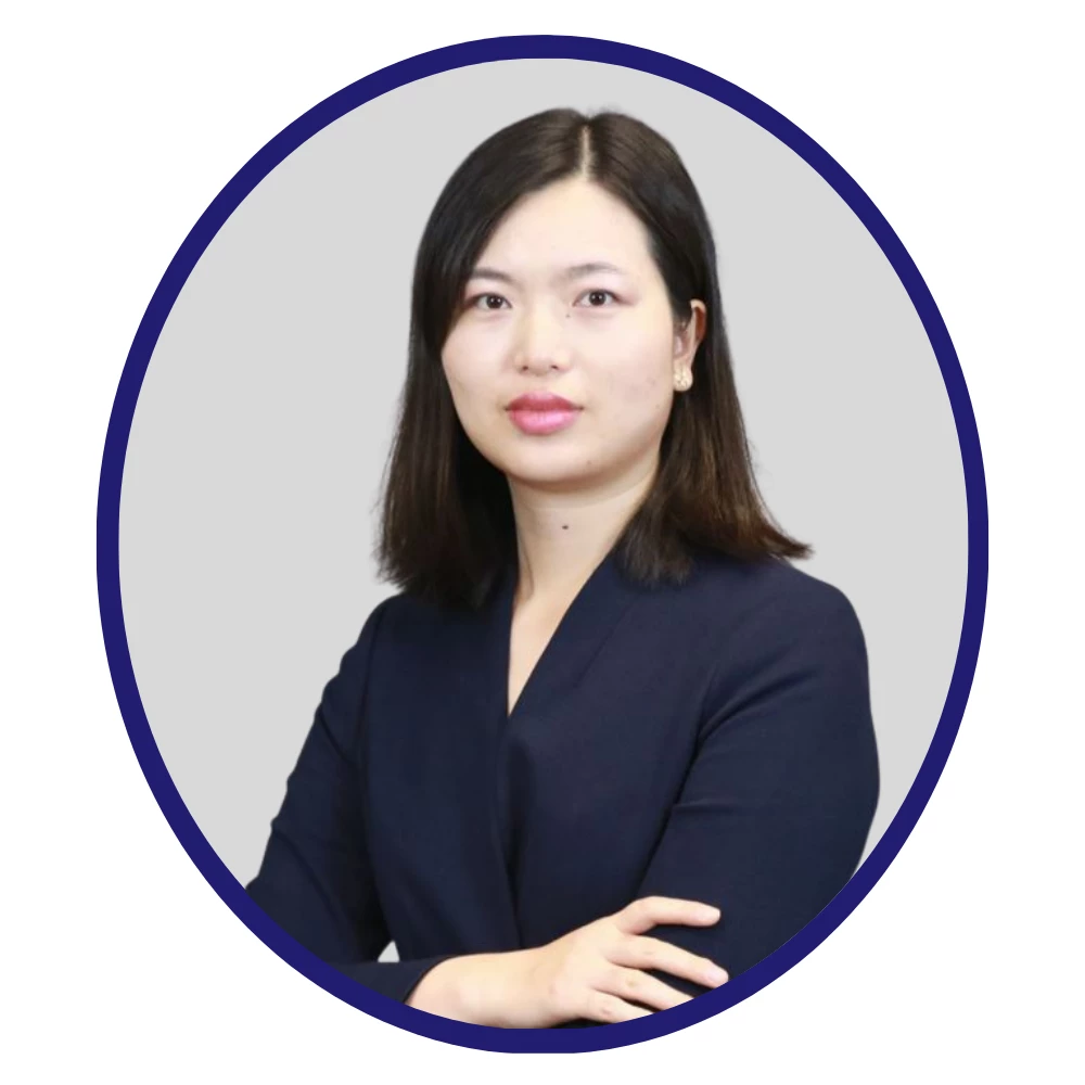 Female business development professional with straight dark hair and a confident pose, wearing a dark blazer, framed in a dark blue oval on a light gray background.