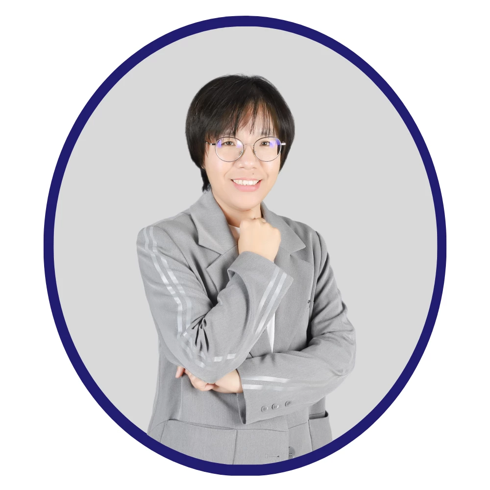 Smiling female scientist with short hair and glasses, wearing a light gray suit with striped sleeves, framed in a dark blue oval on a gray background.