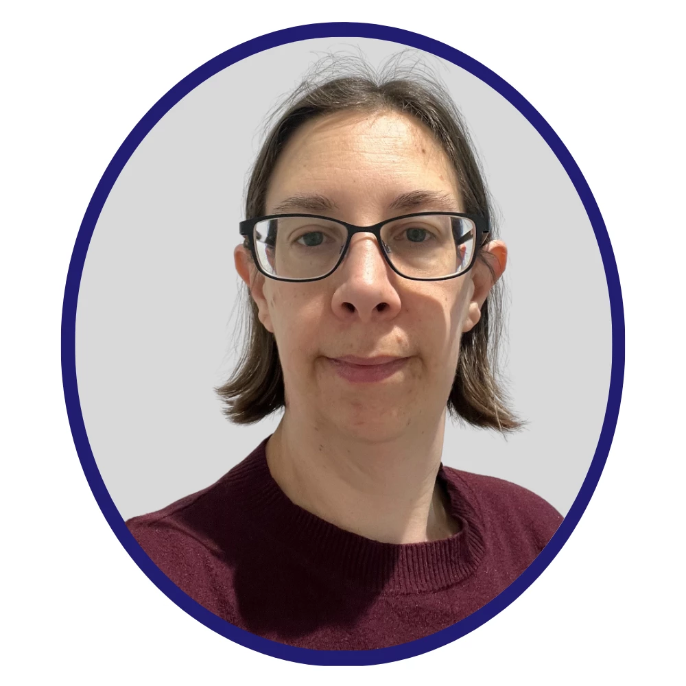 Scientist with short dark hair, glasses, and a burgundy sweater, facing forward against a light grey background with a dark blue circular frame.