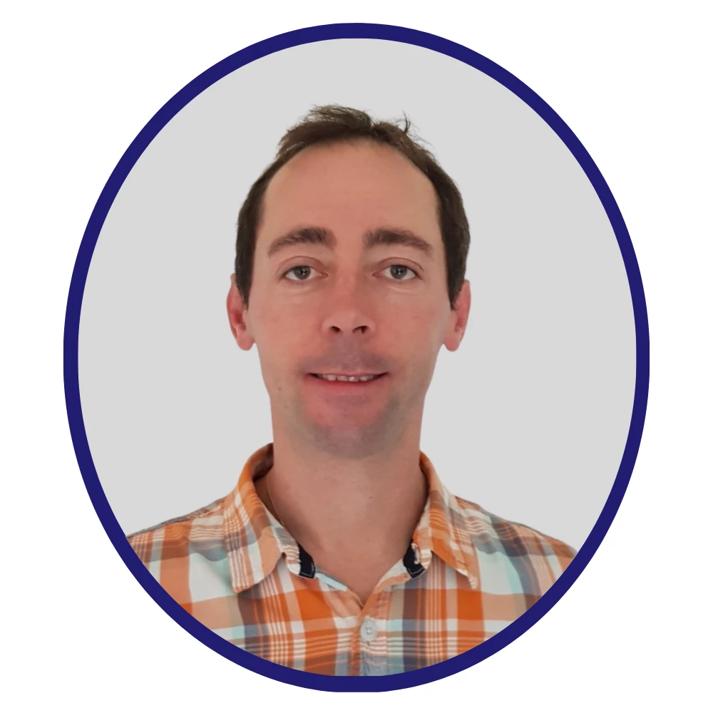 Scientist wearing an orange and blue plaid shirt, facing forward with a neutral expression, framed in a blue oval on a light gray background