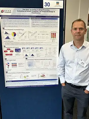 Simon Taylor, VP of DMPK at Pharmaron, standing beside a scientific poster on ADMET prediction for drug discovery at the DMDG Open Meeting 2025.