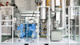 CDMO manufacturing setup with stainless steel reactors and blue motorized pumps used in late-stage manufacturing for chemical or pharmaceutical production.