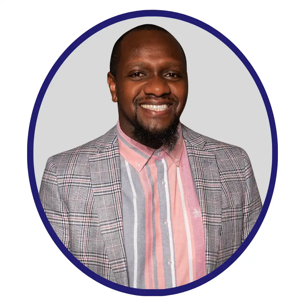 Smiling biopharma professional in a plaid blazer and striped shirt, oval-framed headshot on gray background