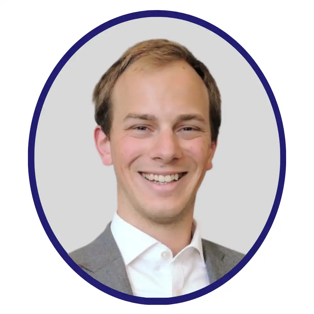 Headshot of Filip Horvath-Gerber, smiling, gray blazer, white shirt, light gray background, navy oval frame